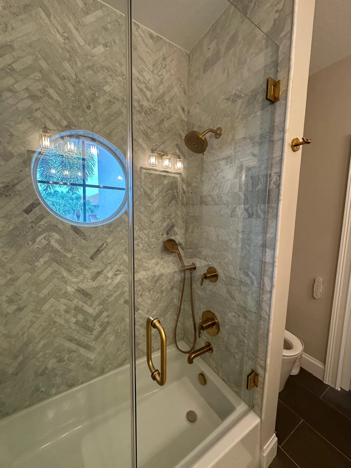 Herringbone tile shower and tub with a glass door, bathroom remodel in Port St Lucie, FL